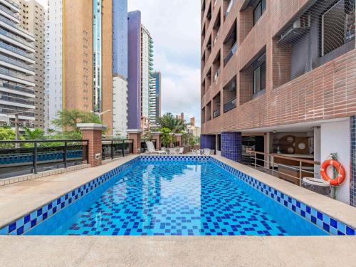 a swimming pool in a building with tall buildings at Deluxe Rooms By Booking Fortaleza in Fortaleza
