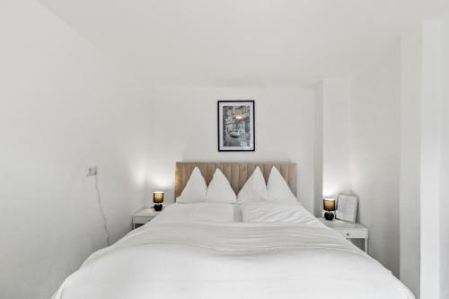 een slaapkamer met een wit bed en 2 nachtkastjes bij StayEasy Apartments Leoben P88 #11 in Donawitz