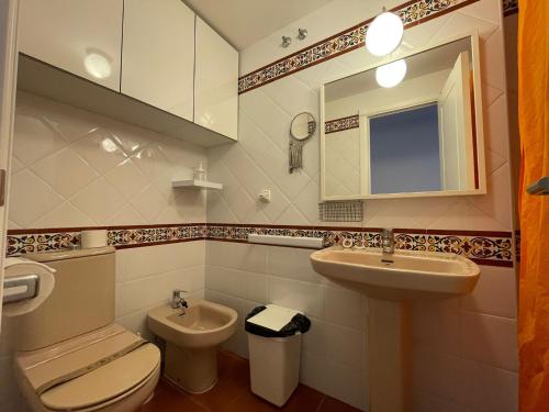 uma casa de banho com um lavatório, um WC e um espelho. em Apartamento premium un dormitorio ALCAUDON em Isla Canela