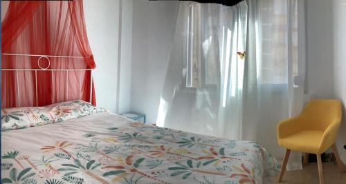 a bedroom with a bed and a chair and a window at Hoja Calá Apartment in Algarrobo-Costa