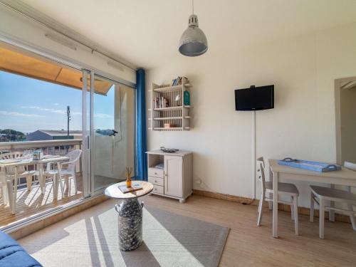 Una sala de estar con una mesa y un balcón. en Studio Ormarine by Interhome, en Le Lavandou