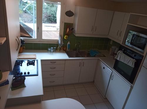 une cuisine avec des armoires blanches, un évier et une cuisinière dans l'établissement Gite 12 à 14 personnes proche Albi, à Castelnau-de-Lévis