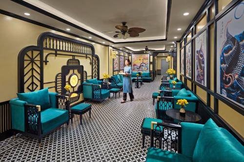 a woman standing in a room with blue couches at Eliana Premio Hotel Hanoi in Hanoi