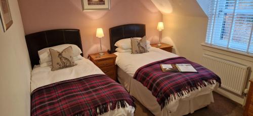 two beds sitting next to each other in a room at Craigbank Guest House in Crianlarich