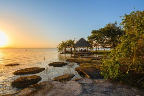 a beach with rocks in the water with a hut at Azulea Bacalar Hotel & Spa - Lagoon Front in Bacalar