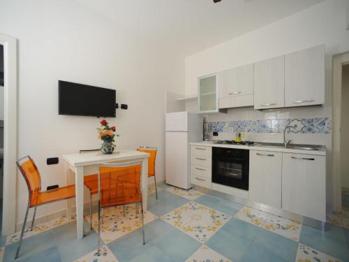 Il comprend une cuisine avec une table et une télévision murale. dans l'établissement Apartment Mimì by Interhome, à Vietri