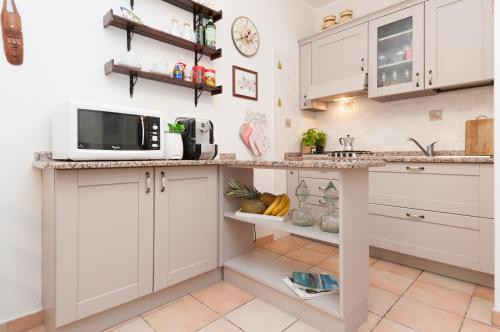 a kitchen with white cabinets and a microwave at Pula - Villetta a 100m dal mare in Fort Village