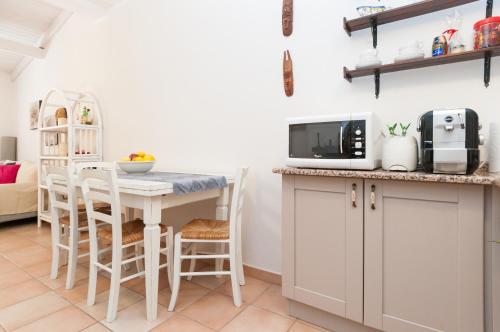 a kitchen with a table with chairs and a microwave at Pula - Villetta a 100m dal mare in Fort Village