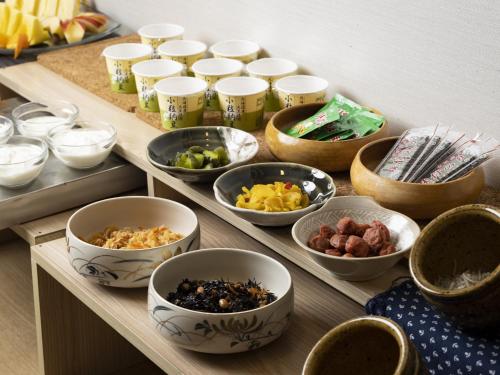 a wooden table with bowls of food on it at Hotel Wing International Kobe - Shinnagata Ekimae in Kobe