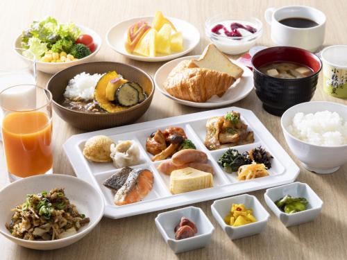 a table with plates of food and bowls of food at Hotel Wing International Kobe - Shinnagata Ekimae in Kobe