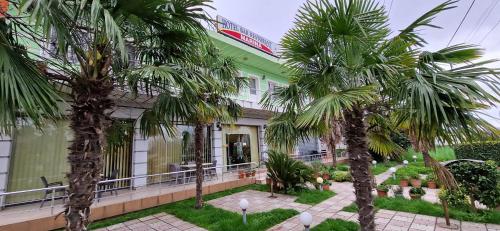 un edificio verde con palme di fronte di Hotel Bar Restorant Marina a Mjedë