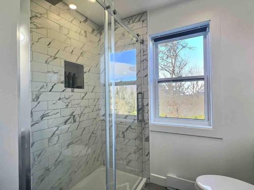 a bathroom with a shower and a toilet and a window at Condo sur 2 étages in Saint-Faustin