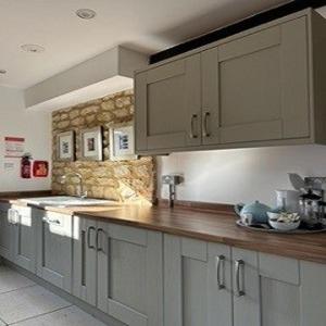 a kitchen with white cabinets and a wooden counter top at Badgers Sett at Tove Valley Cottages in Towcester