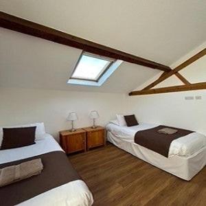 a attic bedroom with two beds and a window at Badgers Sett at Tove Valley Cottages in Towcester