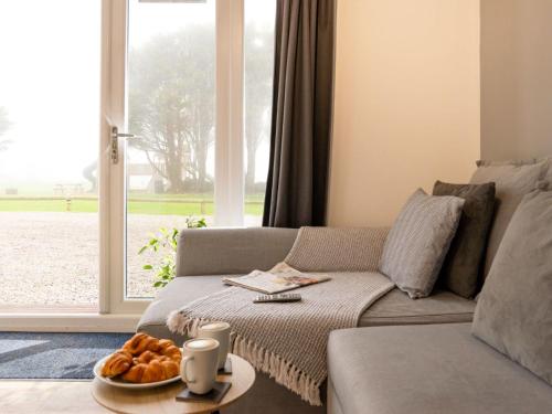 a living room with a couch and a table with bread at Chalet Wheal Prosper Hot Tub Lodge by Interhome in Helston