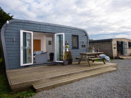 a tiny caravan with a wooden deck and a picnic table at Chalet Wheal Tor Lodge by Interhome in Helston