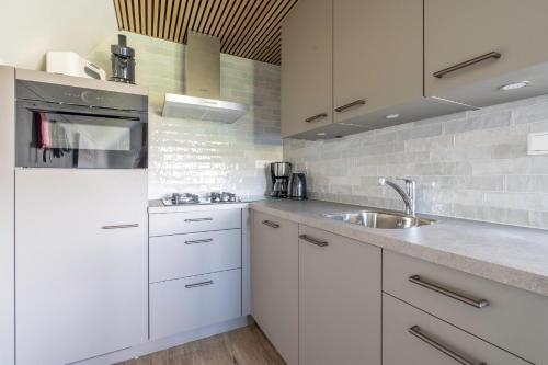 a kitchen with white cabinets and a sink at Nieuwlanderweg 75 in De Waal