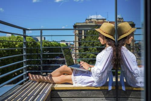 a woman sitting on a bench with a laptop at Kaunas City in Kaunas