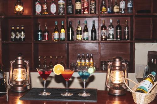 a bar with three cocktails on a counter with bottles of alcohol at Drunken Elephant Mara in Sekenani