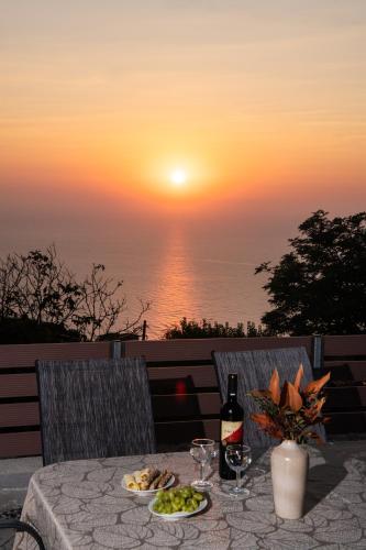 a table with a bottle of wine and plates of food at Athanion Sunset House in Athani
