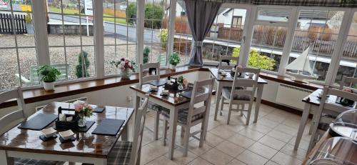 a restaurant with tables and chairs and windows at Craigbank Guest House in Crianlarich