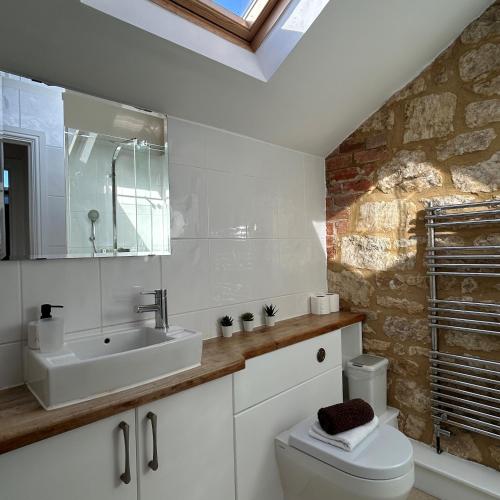 Baño blanco con lavabo y aseo en Badgers Sett at Tove Valley Cottages, en Towcester