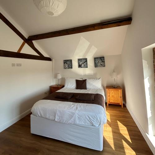 a bedroom with a white bed in a attic at Badgers Sett at Tove Valley Cottages in Towcester