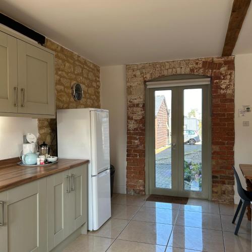 a kitchen with a white refrigerator and a door at Badgers Sett at Tove Valley Cottages in Towcester