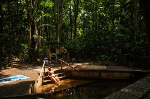 a woman sitting on the steps of a wooden deck in the jungle at Aconchego Gaia in Alter do Chao