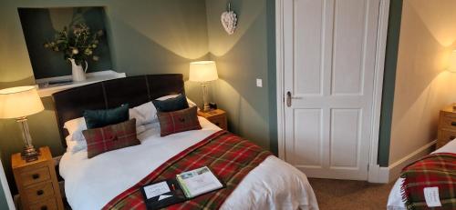 a bedroom with a bed and two lamps and a door at Craigbank Guest House in Crianlarich
