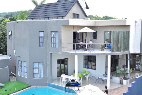 una casa con piscina y gente sentada en un balcón en Naldorado Executive Villa en Nelspruit