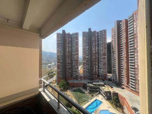 einen Balkon mit Blick auf eine Stadt mit hohen Gebäuden in der Unterkunft Acogedor Apto en Bello, cerca del Metro in Bello