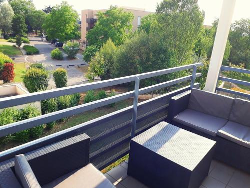 un balcón con un banco y una mesa. en Le Cosy Appart - Balcon parking - Proche Eurexpo Stade, en Saint-Priest