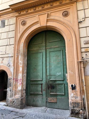 eine grüne Tür an der Seite eines Gebäudes in der Unterkunft NAPOLI VIBES Rooms in Neapel