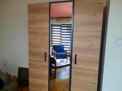 um espelho com uma cadeira azul num quarto em Dardani em Pristina