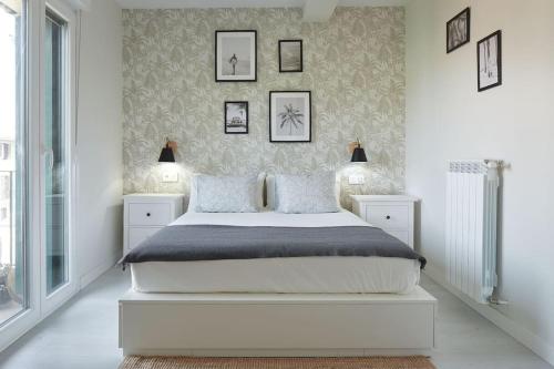 a bedroom with a white bed and framed pictures on the wall at EARRA - Casa Fabiola, centro y a 2 min de la playa in Zarautz