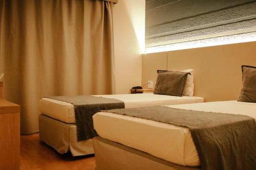 a room with two beds in a room at Carlton Plaza Baobá in Taubaté