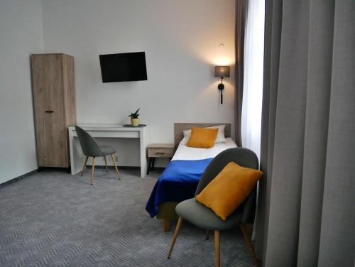 ワルシャワにあるCentrum Szkoleniowo-Konferencyjne Społemのベッド、椅子、デスクが備わる客室です。