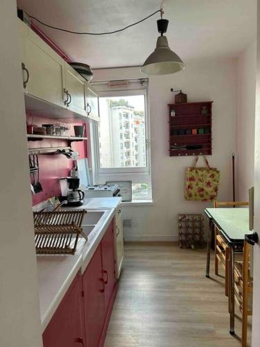 une cuisine avec des placards rouges et une fenêtre dans l'établissement 2 pièces Lumineux proche du Parc Buttes Chaumonts, à Paris