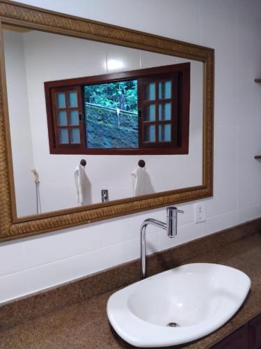 a bathroom mirror with a sink and a window at Bromélia Sabiá & Cia in Teresópolis