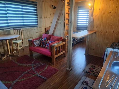 uma sala de estar com um sofá vermelho numa cabina em Casa, central a orilla de playa em Puerto Williams