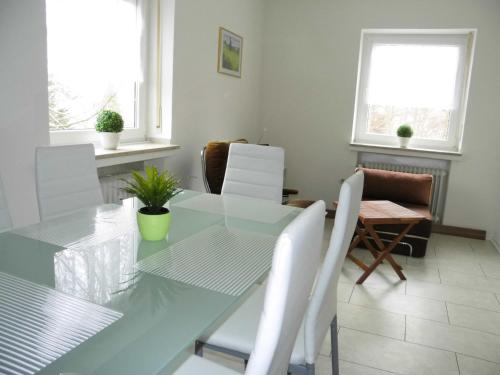 a dining room with a glass table and white chairs at Ferienwohnung Tante Martha in Monschau