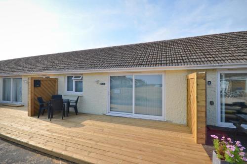a house with a wooden deck with a table and chairs at The Hideaway, 65 Salterns Beach Bungalows, Seaview in Seaview