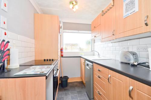 a small kitchen with wooden cabinets and a sink at 32 Sandown Bay Holiday Centre in Brading