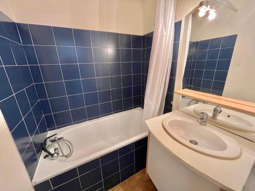 une salle de bain carrelée bleue avec un lavabo et une baignoire dans l'établissement Studio climatisé en bord de mer avec terrasse et parking privé - FR-1-716-43, à La Grande Motte