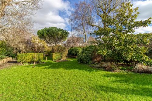 a garden with green grass and trees and bushes at La Villa Authentique - Jacuzzi, babyfoot in Bourbourg