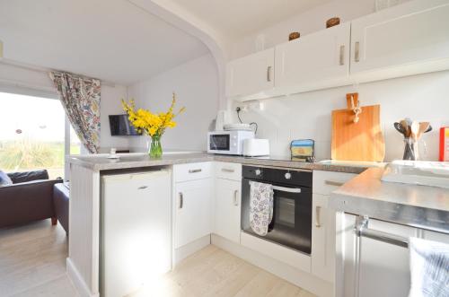 a kitchen with white cabinets and a counter top at Lobster Pot, 66 Salterns Beach Bungalows, Seaview in Seaview