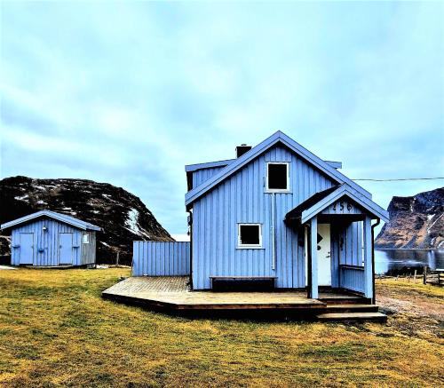 two blue buildings in a field with mountains in the background at Haukland Panorama in Offersøya