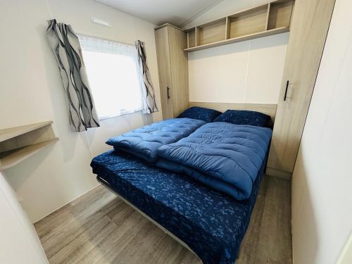 un letto in una piccola camera con un piumone blu di DD 58 - Camping de Duindoorn - AIRCO a IJmuiden