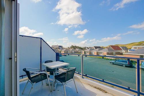 a balcony with a table and chairs and a view of a street at Appartement Seinpost 26 - Callantsoog aan Zee in Callantsoog
